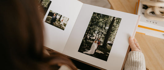 A woman looking through her wedding Matted Album. The album is open on a page that shows a couple portrait in the woods with overlayed white matts.